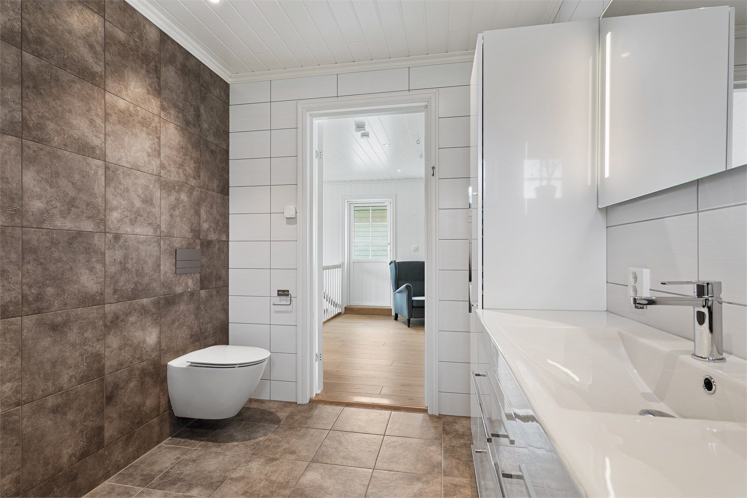Det lekre badet i andre etasje har store fliser på gulv og vegger, gulvvarme og downlights i himling.