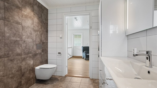 Det lekre badet i andre etasje har store fliser på gulv og vegger, gulvvarme og downlights i himling.