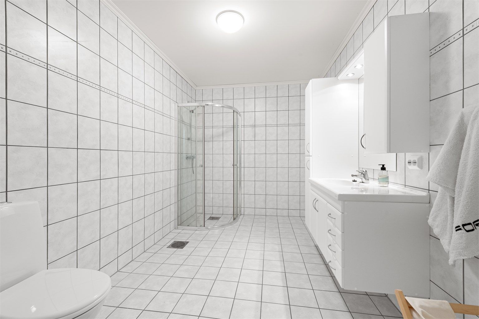 Badet i underetasjen tilhørende hoveddelen av boligen. Flislagt gulv med gulvvarme, flislagte vegger og stor og romslig innredning. Wc.