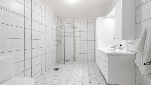 Badet i underetasjen tilhørende hoveddelen av boligen. Flislagt gulv med gulvvarme, flislagte vegger og stor og romslig innredning. Wc.