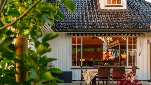 Stort vindu i stuen med hyggelig utsyn over hagen og uteplassene og hagen.