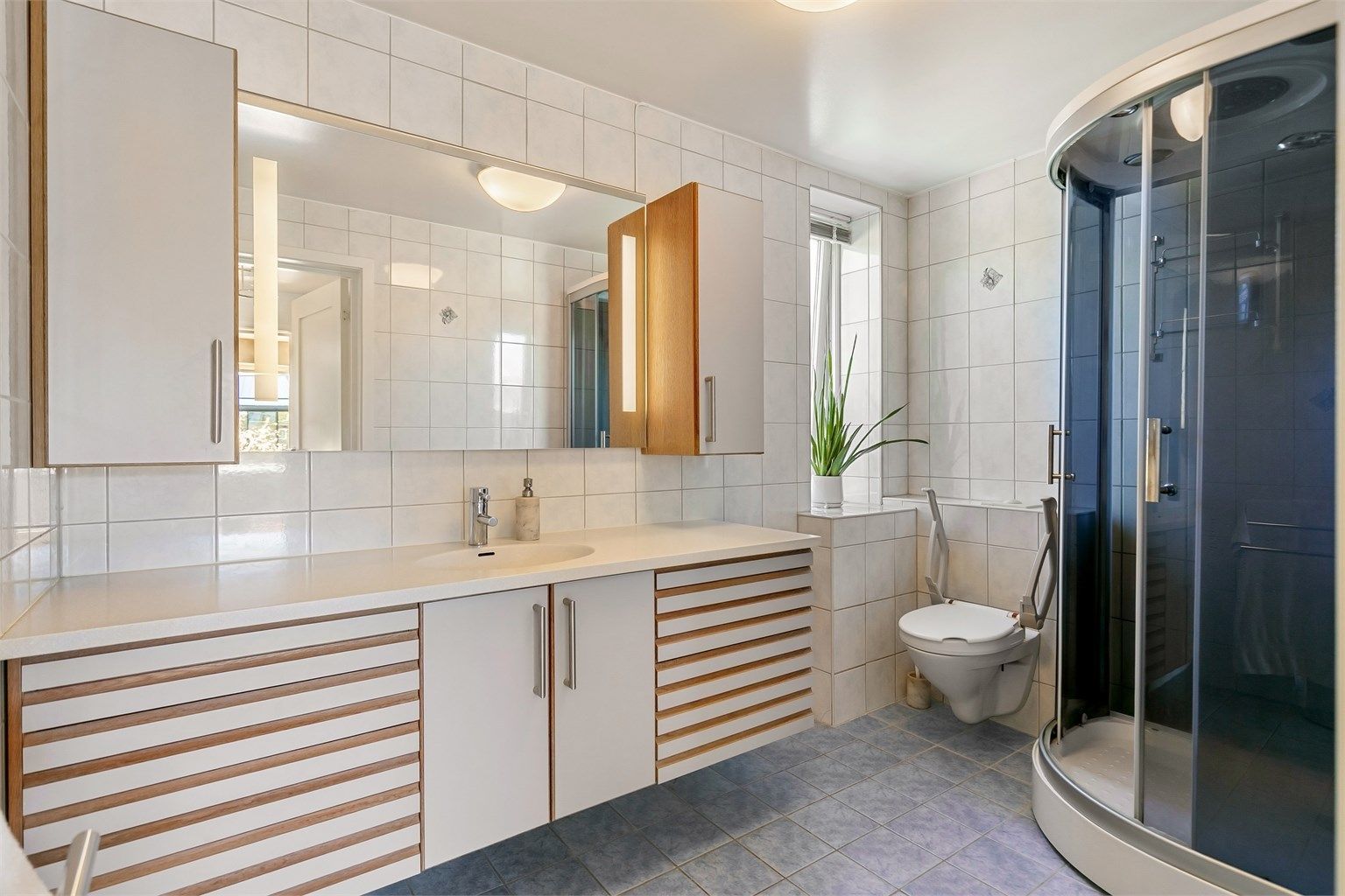 Badet i andre etasje har flislagt gulv med gulvvarme og flislagte vegger.