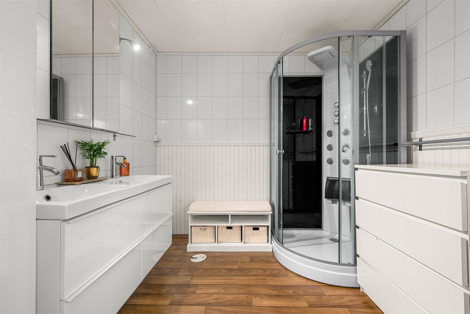 Videre er badet innredet med dobbeltservant med overskap med speil og lys, dusjkabinett og toalett. 
