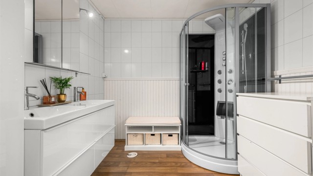 Videre er badet innredet med dobbeltservant med overskap med speil og lys, dusjkabinett og toalett.