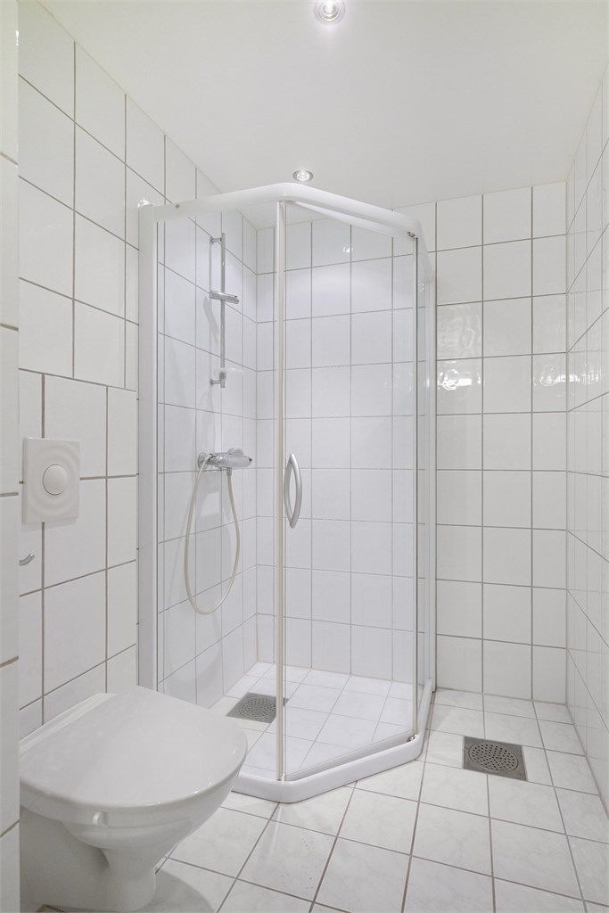 Badet er utstyrt med dusjkabinett og vegghengt toalett. Lyse og tidløse materialvalg.