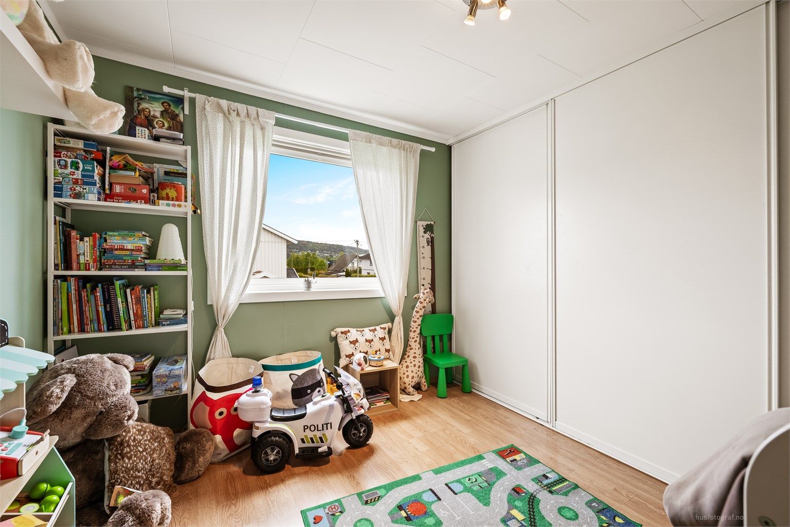 Et av tre soverom i 2. etasje, her med en stor skyvedørsgarderobe.