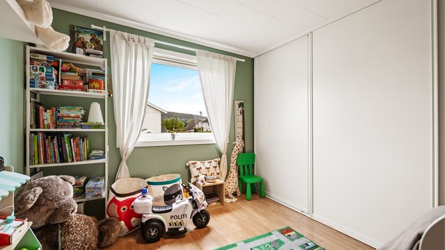 Et av tre soverom i 2. etasje, her med en stor skyvedørsgarderobe.