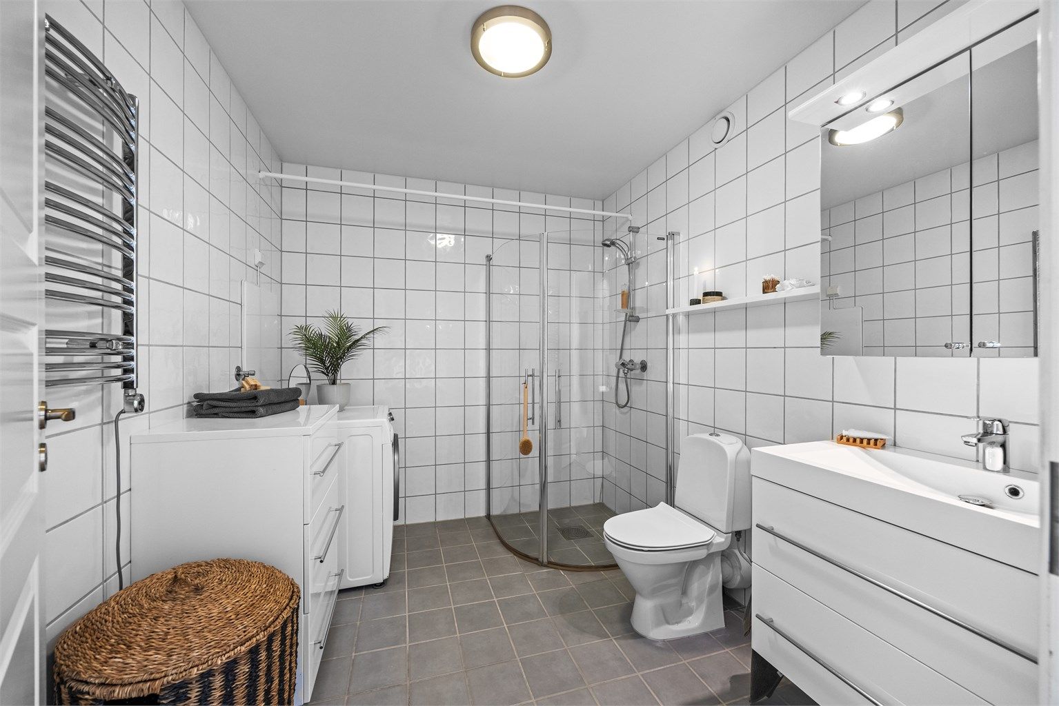 Stort bad, med fliser på vegger og gulv. Varmekabler og opplegg for vaskemaskin/tørketrommel.