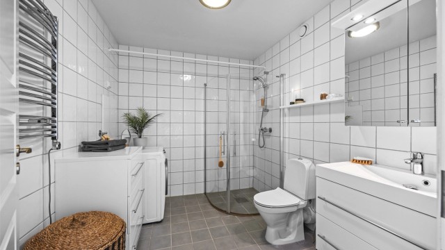 Stort bad, med fliser på vegger og gulv. Varmekabler og opplegg for vaskemaskin/tørketrommel.