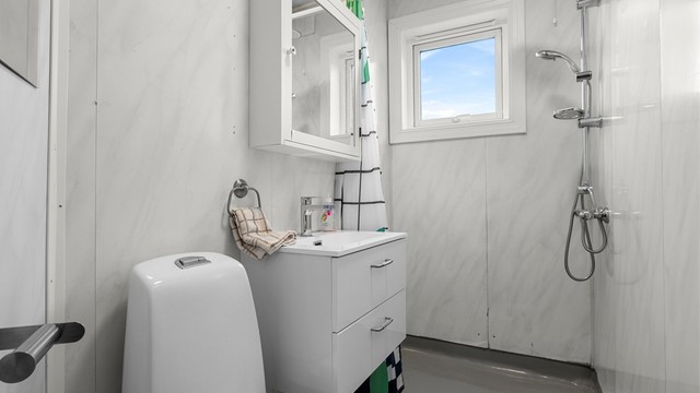 Badet har en funksjonell utforming med dusjhjørne, servant med oppbevaring og toalett.