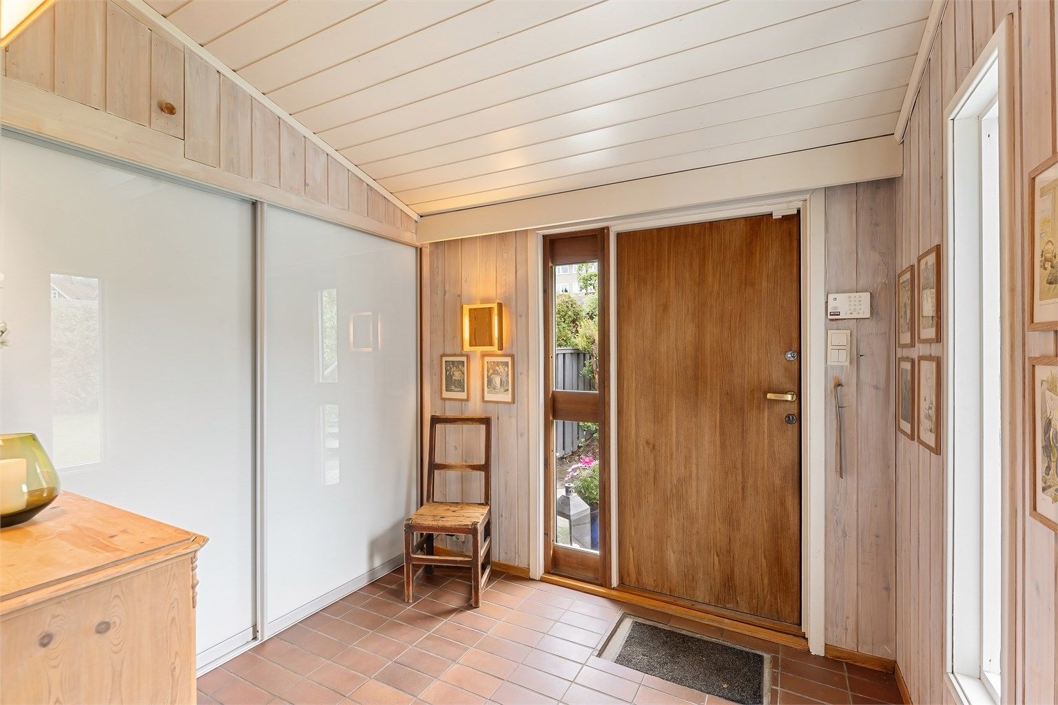 Romslig entré med flislagt gulv, gulvvarme og en stor skyvedørsgarderobe for effektiv oppbevaring.