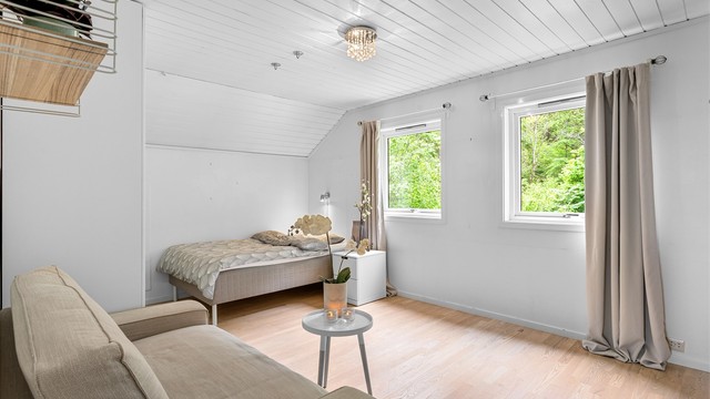 Soverommet i andre etasje er lyst og romslig, med plass til både seng og en liten sittegruppe. Rommet er ikke bruksendret/omsøkt.