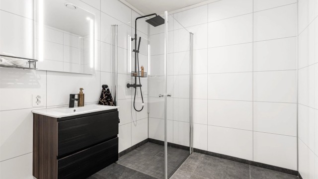 Vegghengt servantskap med ovenpåliggende servant og ett-greps armatur. Speil med integrert belysning over servant. Stikkontakt på vegg.