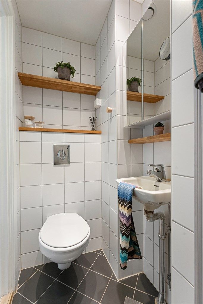 Badet er innredet med vegghengt toalett, servant og speilskap.
