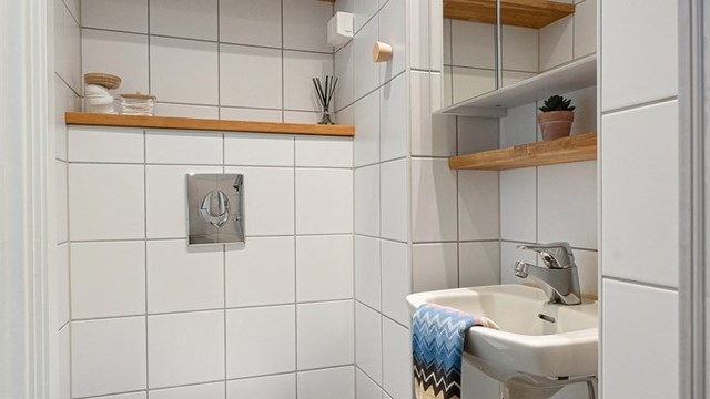 Badet er innredet med vegghengt toalett, servant og speilskap.