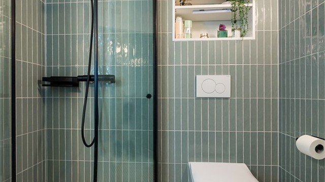 Badet er innredet med vegghengt toalett og egen dusjsone med innfellbare glassdører.