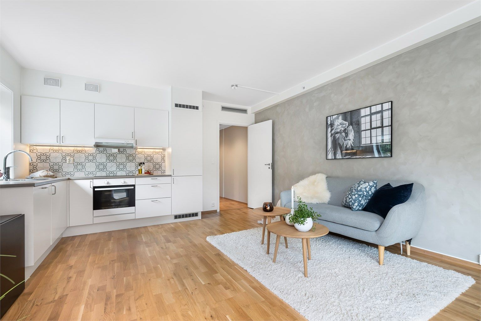 Leiligheten har åpen stue/kjøkken løsning - stilrene overflater og parkett på gulv. 