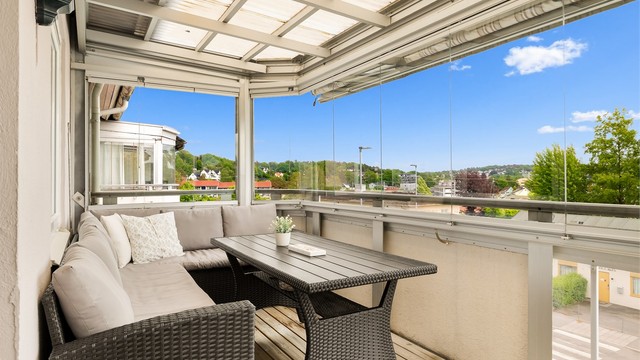 Fra stuen er det utgang til en overbygd og innglasset balkong på 10 kvm. Balkongen er belagt med terrassebord og har rekkverk i glass og metall. Det er montert utebelysning.