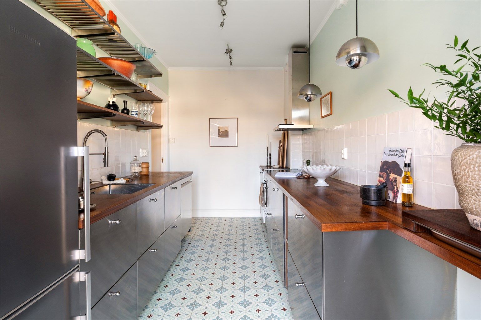 Kjøkkenet ble stilrent oppgradert i 2022, med fronter i metall og en solid benkeplate i heltre. Herfra er det direkte utgang til balkongen.