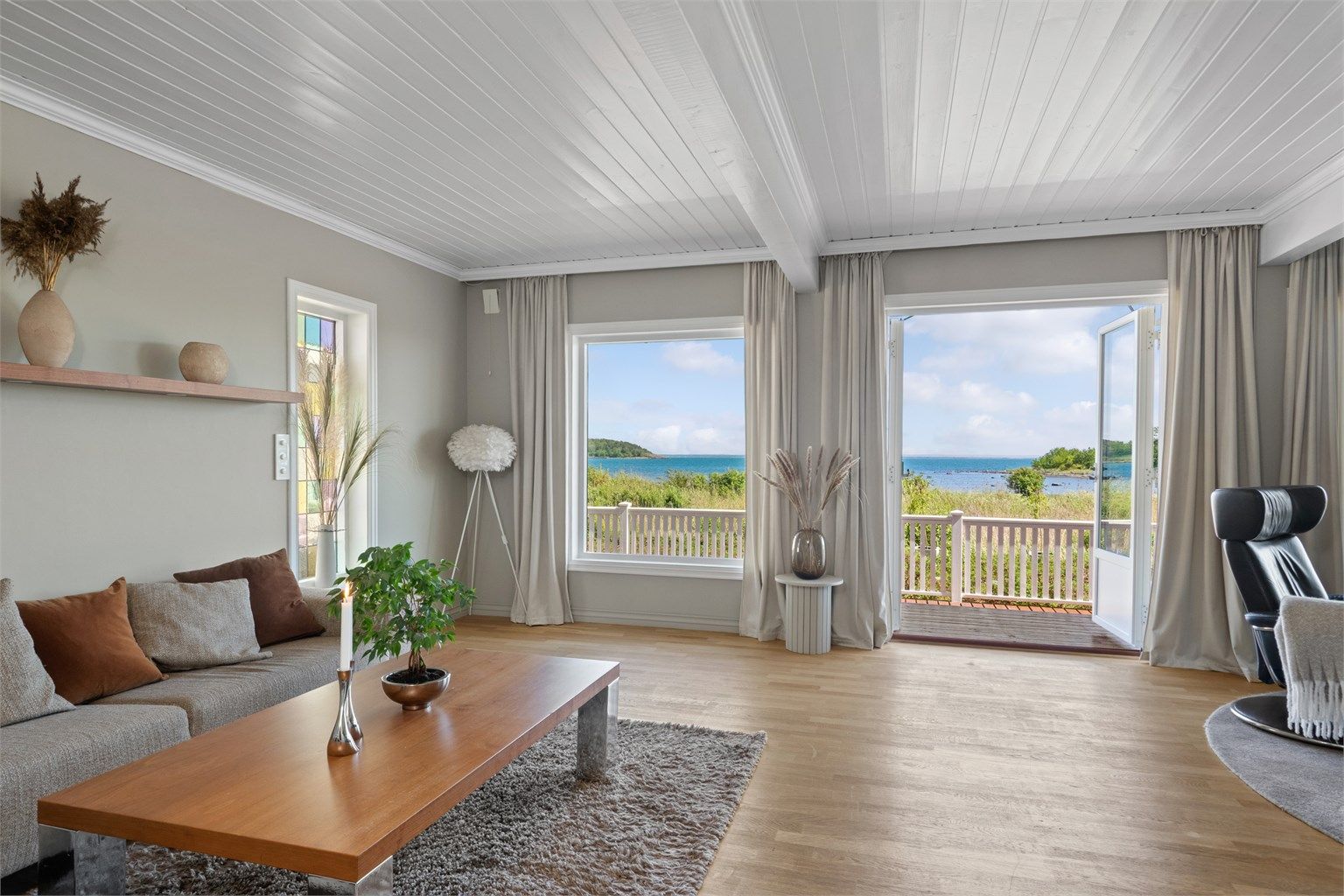 Stuen er lys og trivelig med store vindusflater og tofløyede terrassedører som ivaretar den nydelige utsikten til stranda og sjøen. 