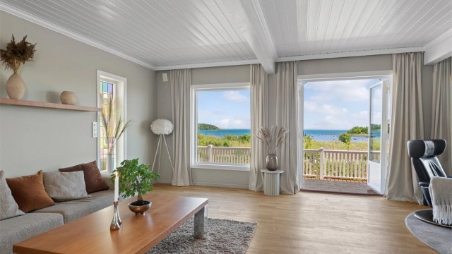Stuen er lys og trivelig med store vindusflater og tofløyede terrassedører som ivaretar den nydelige utsikten til stranda og sjøen.
