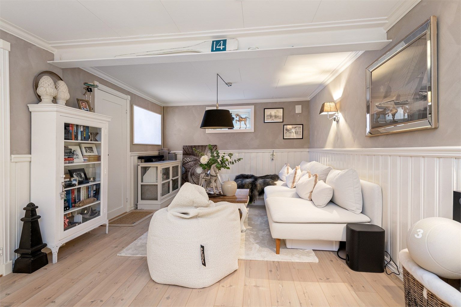 Kjellerstuen har en-stavs laminat på gulvet og en kombinasjon av malt brystningspanel og tapet på vegger
