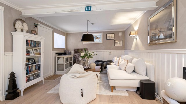 Kjellerstuen har en-stavs laminat på gulvet og en kombinasjon av malt brystningspanel og tapet på vegger