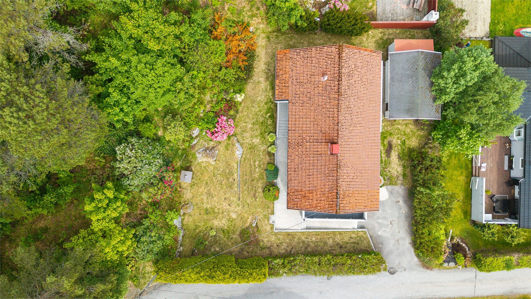 Boligen sett fra luften, med en oversikt over tomten og taket belagt med takstein.