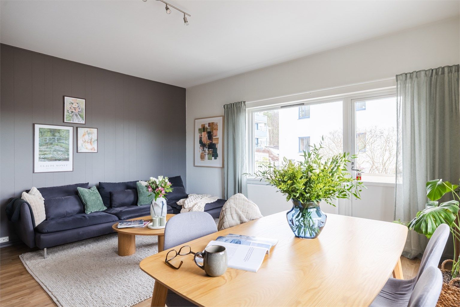 Åpen og hyggelig stue med flere store vinduer på flere veggflater som slipper inn rikelig med lys. 