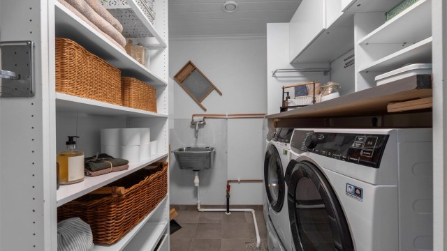 Videre inn fra badet i 1. etasje er det et eget vaskerom med vegghengt utslagsvask i rustfritt stål med armatur og sprutplate på veggen bak.