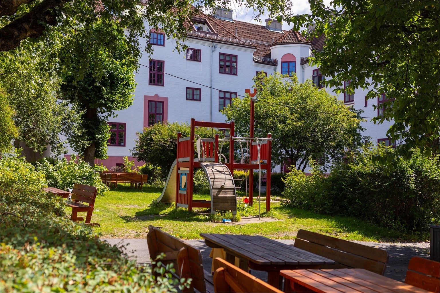 Store grøntområder, sitteplasser og frodig beplantning gjør bakgården til et naturlig samlingssted gjennom hele året.