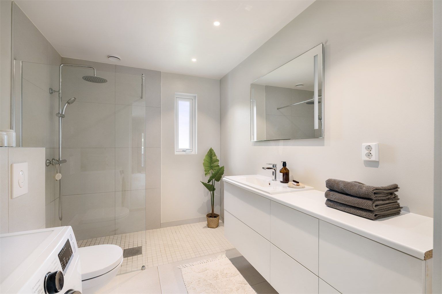 Badet har elektrisk gulvvarme, downlights i taket og opplegg for vaskemaskin. Et lekkert og innbydende bad. 