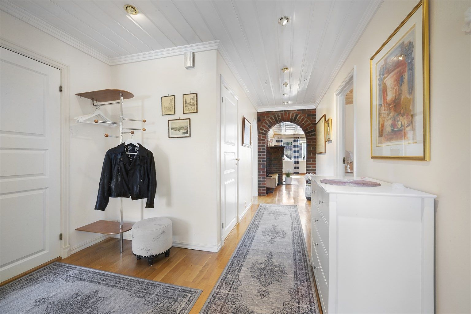 Velkommen inn i en romslig entré med parkett på gulv og lyse vegger