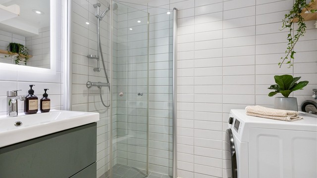 Badet har dusjnisje med glassdører og opplegg for vaskemaskin.