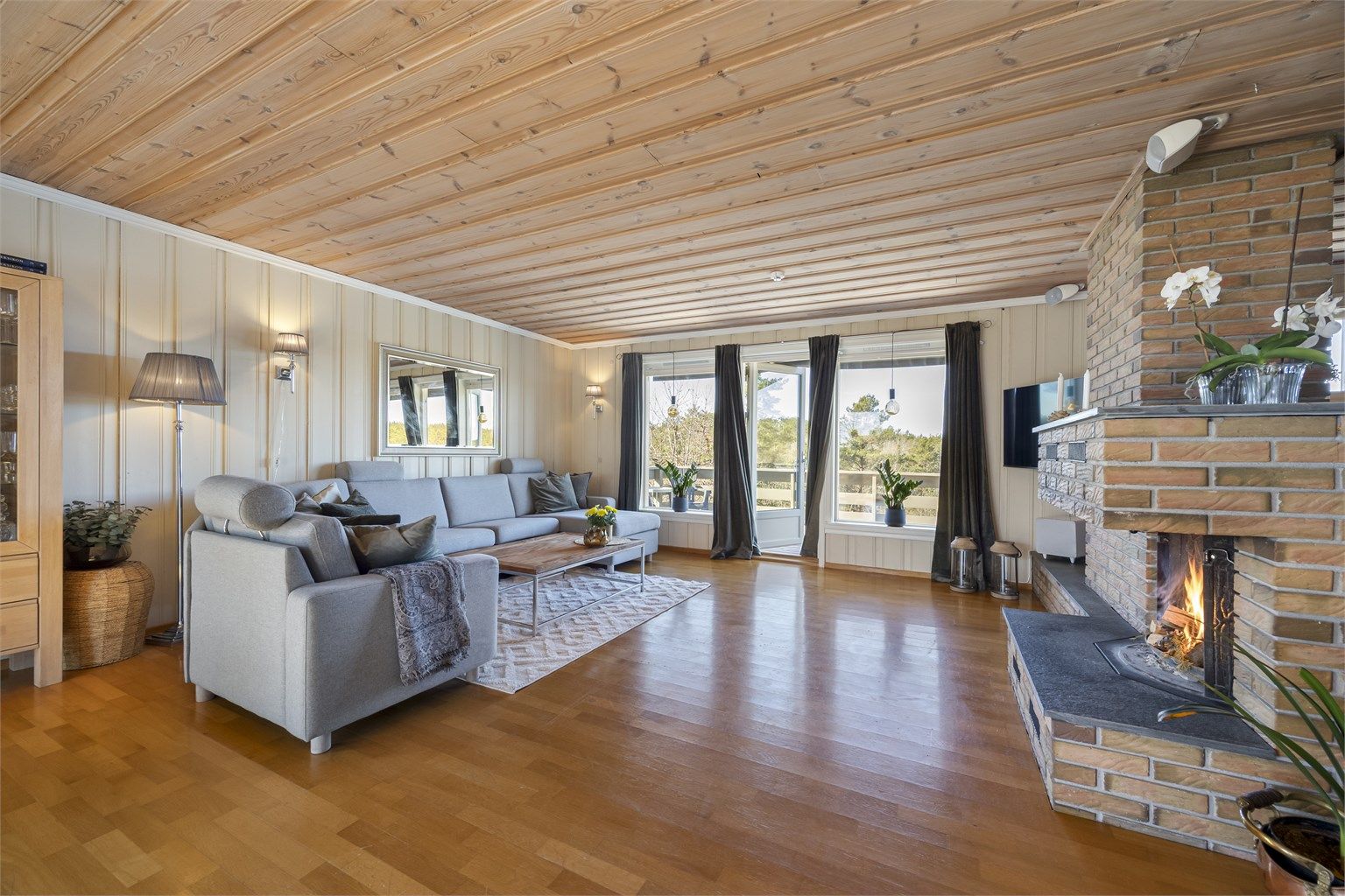 Romslig stue med god plass til en stor sofagruppe. Den sentralt plasserte peisen gir varme og en hyggelig atmosfære.