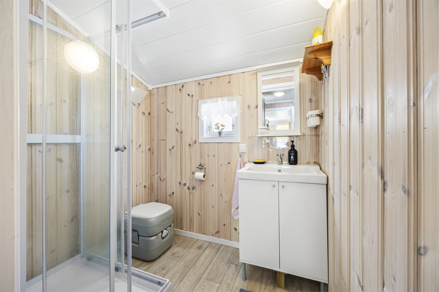 Badet har gulvbelegg, panel på veggene og servantinnredning.