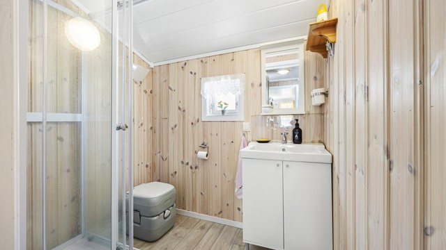 Badet har gulvbelegg, panel på veggene og servantinnredning.