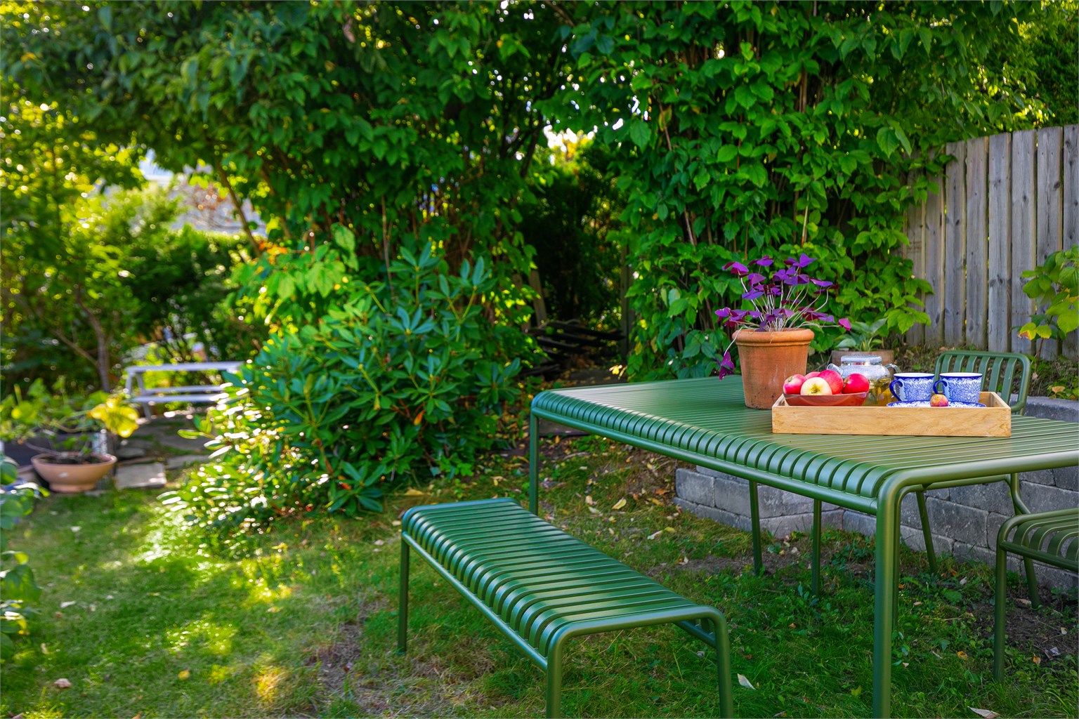 Skjermet hageparsell med plenarealer og variert beplantning.