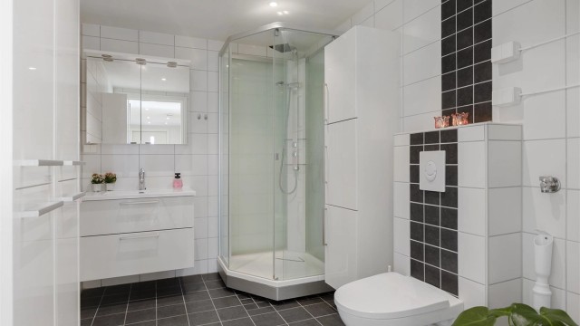 Romslig bad med flislagt gulv med gulvvarme og downlights i taket.