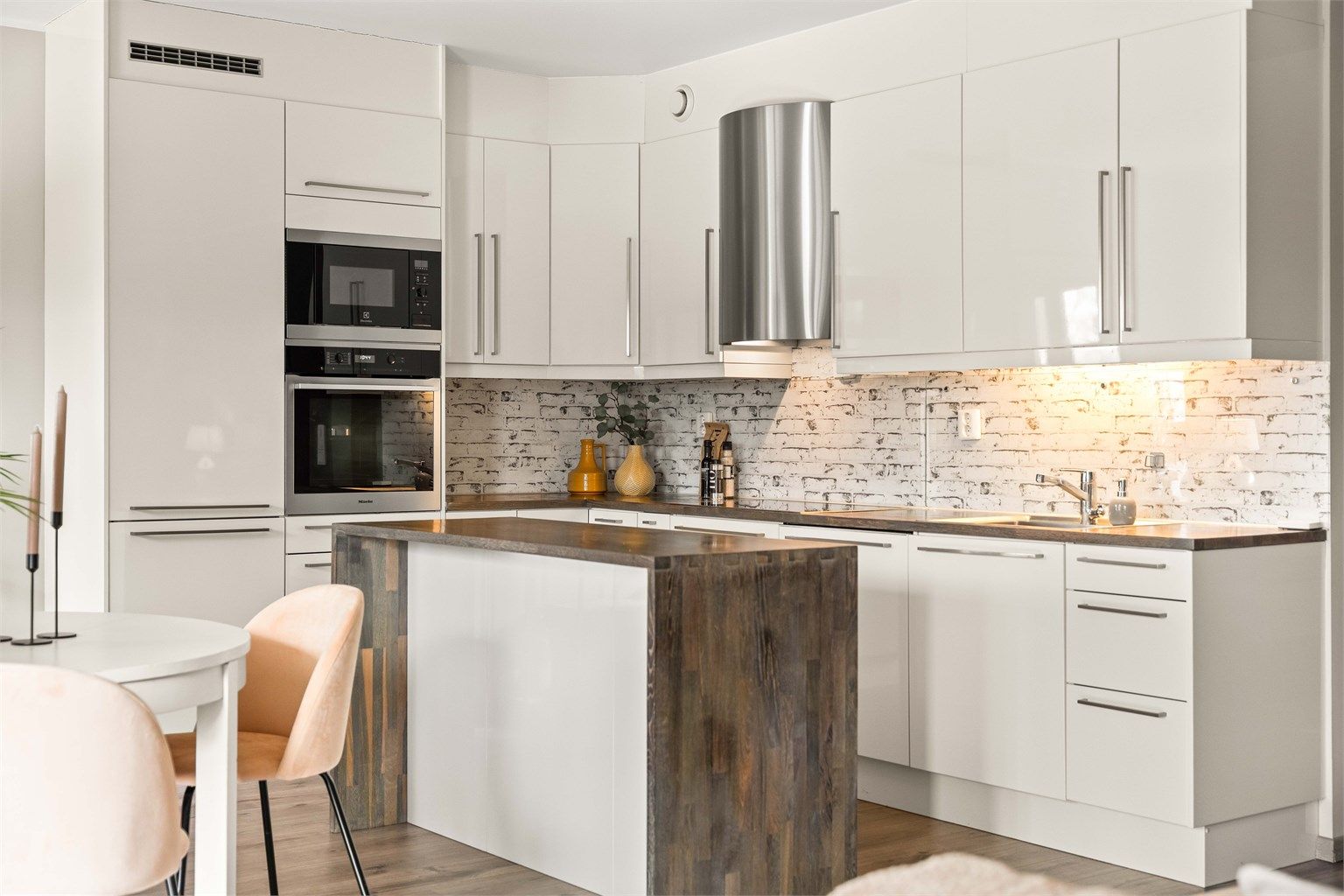 Moderne og funksjonell kjøkkeninnredning med integrerte hvitevarer og praktisk kjøkkenøy. Slette fronter kombinert med treverk gir et tidløst uttrykk. God belysning og smarte løsninger sikrer en behagelig arbeidssone.