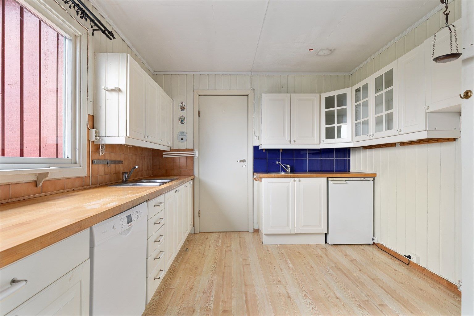 Kjøkkenet er innredet med over- og underskap i lyse profilerte fronter