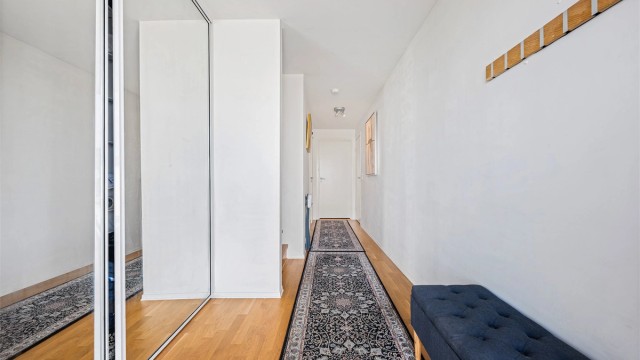 Entré med parkett på gulv, lyse vegger og romslig skyvedørsgarderobe med speilfronter.