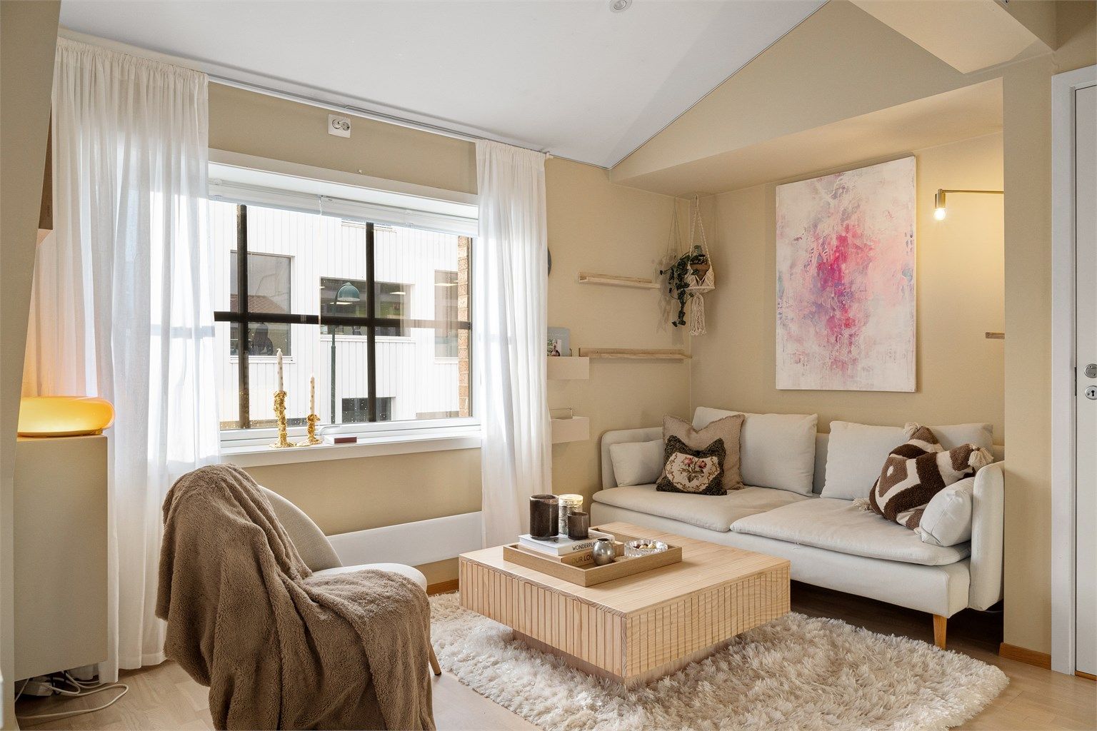 Stue malt i moderne farger med stort vindu samt plass til sittegruppe. 