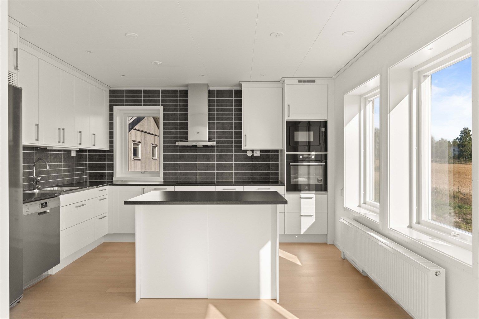 Kjøkken med hvite profilerte fronter, laminert benkeplate og hvitevarer fra Electrolux.