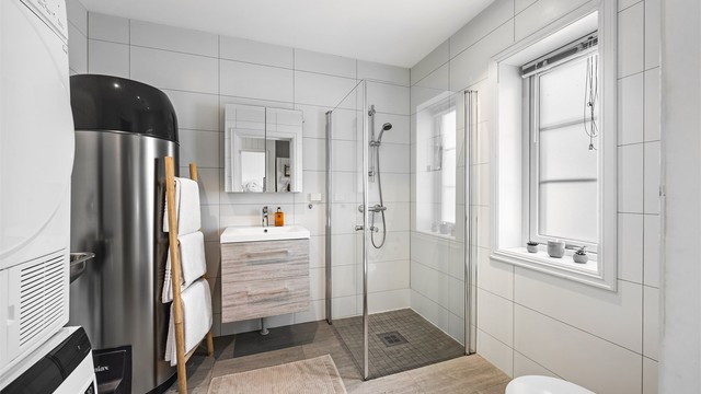 Badet i første etasje har flislagte overflater, gulvvarme og dusjhjørne.