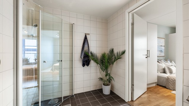 Badet har innfellbare dusjdører av glass og opplegg for vaskemaskin.