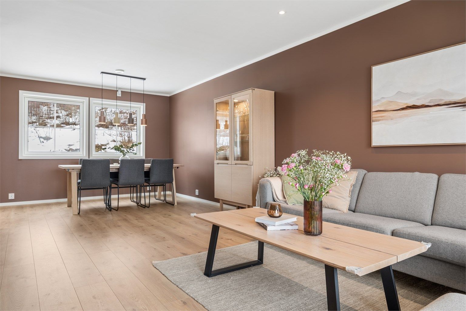 Her er det god plass til både sofagruppe og spisebord, og rommet oppleves lyst og trivelig.