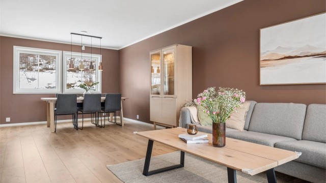 Her er det god plass til både sofagruppe og spisebord, og rommet oppleves lyst og trivelig.
