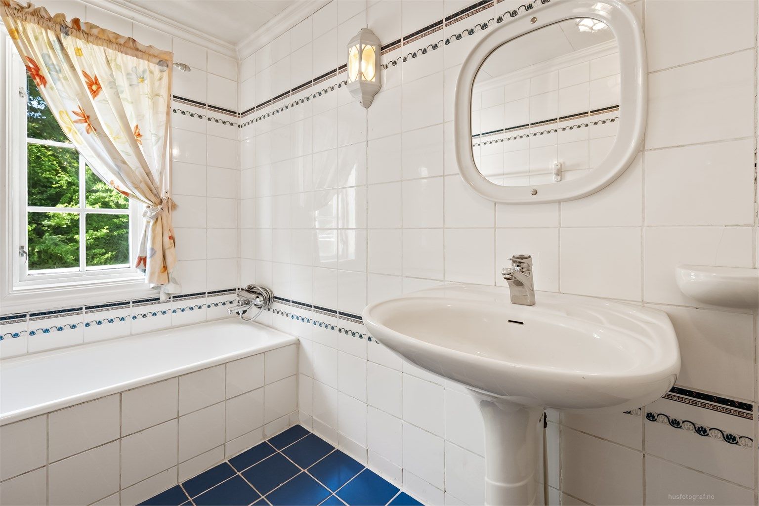 Bad i første etasje, innredet med badekar og flislagte overflater.