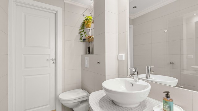 Badet er utstyrt med vegghengt toalett med innebygget sisterne.
